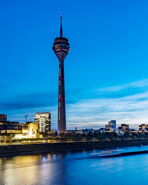 The Rhine Tower in Düsseldorf, the banks of the Rhine and the Rhine at dusk.