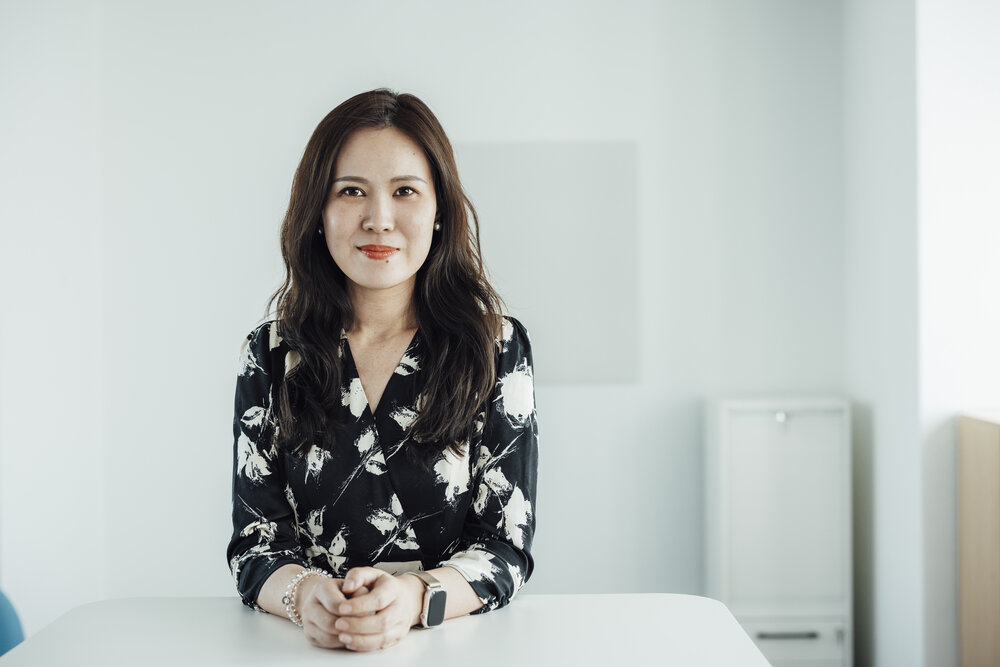 A portrait photograph of a smartly dressed woman sitting behind an office desk.