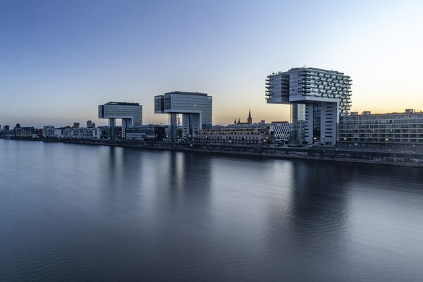 View of the crane houses in Cologne's Rheinauhafen at dusk, with the architecture reflected in the Rhine.